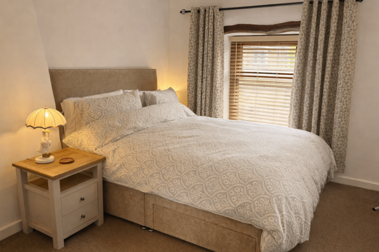 Main king size bedroom with white linen and exposed beams